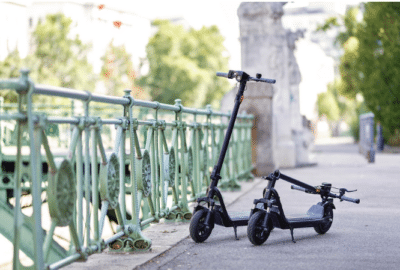 Der NIU KQi 100F E-Scooter E-Scooter steht an einem Gitter zu einem Fluß direkt vor einer Brücke